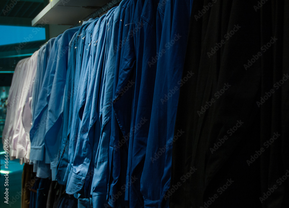 Men's plaid shirts in different colors on hangers in a retail shop