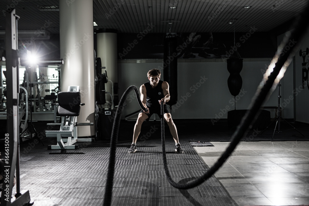 Fitness man working out with battle ropes at gym. Battle ropes