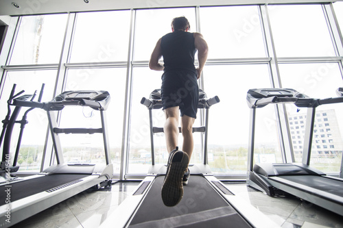 Foto Back view of young man athlete with running on treadmill in gym