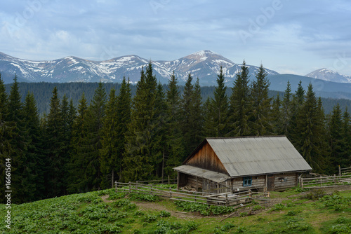 Farm in the Carpathians on the background of snow-capped mountains. 