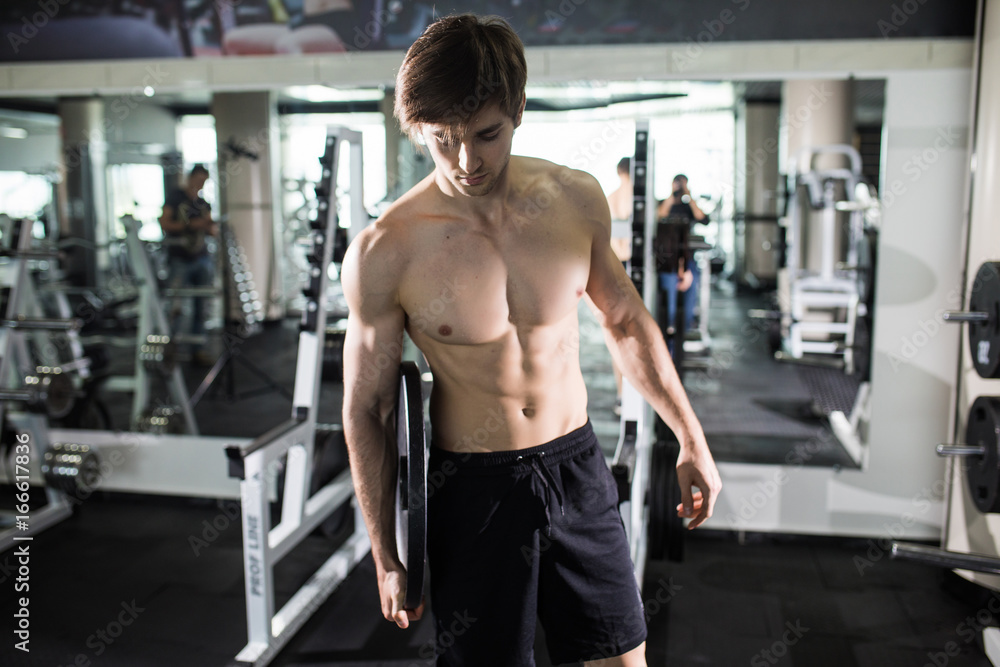 young man flexing muscles with barbell in gym. Sport young man flexing muscles with barbell in gym. Sport