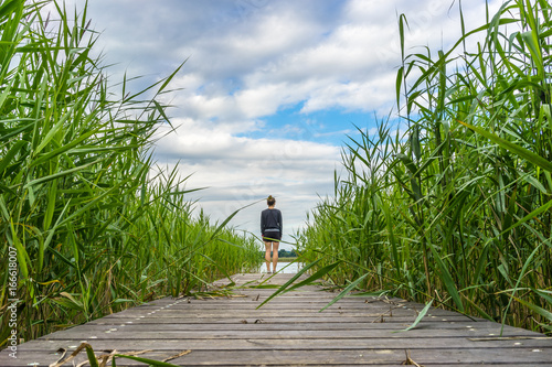 Φωτογραφία Young woman standing on a jetty at a lake