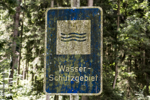 old rusty vintage forgotten german sign in forest translation wasser schutzgebiet means water reserve photo