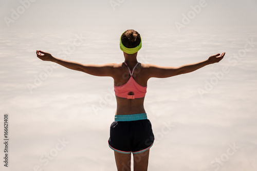 woman enjoying the nature in the mountains and looking on sky with raised hands.