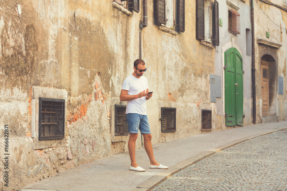 Modern guy using cellphone in the European city.