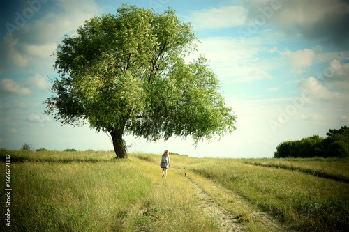 Girl with a dog walking on a road in the countryside