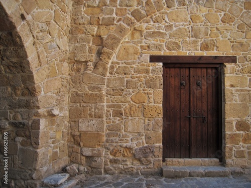 Old wooden door in the stone wall, ancient Mediterranean style. © Tatiana