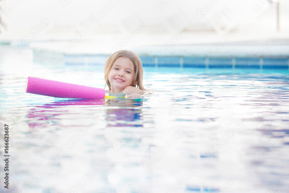 Kleinkind mit Schwimmnudel im Schwimmbad