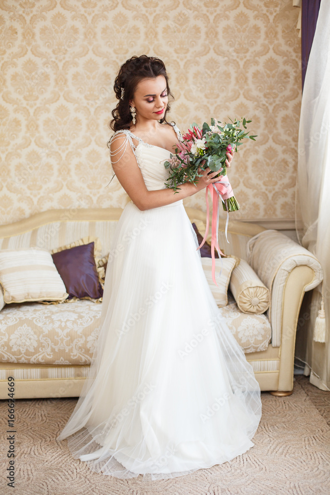 Beautiful young Bride with dark hairs in a bedroom. Classic white wedding dress. Half-length portrait Beautiful young Bride with dark hairs in a bedroom. Classic white wedding dress. Half-length portrait