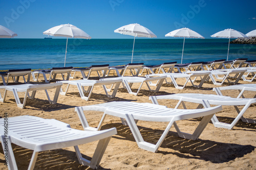 Beautiful empty beach with rows of sun beds under straw umbrellas © sosiukin