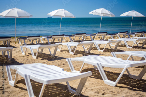 Beautiful empty beach with rows of sun beds under straw umbrellas © sosiukin