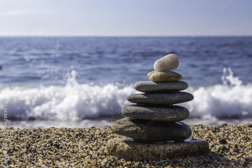 Fototapeta premium Balanced stones on the beach of Sardinia Island. Waves background.