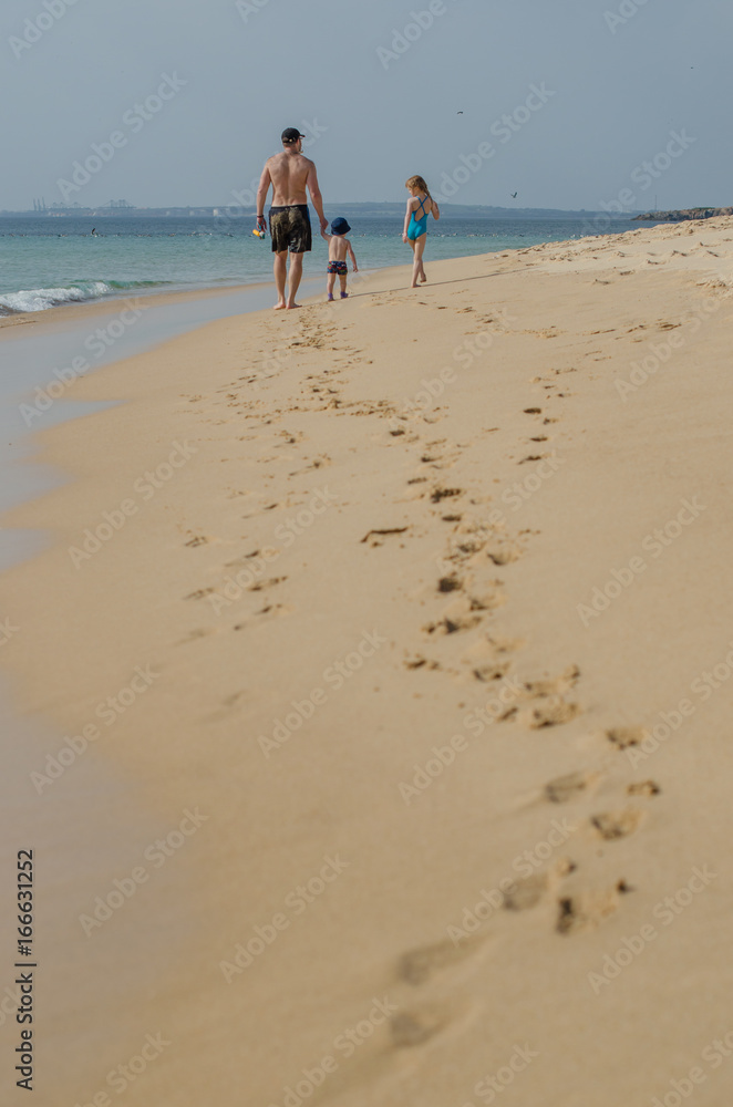 Man and children walking along the ocean shore Man and children walking along the ocean shore