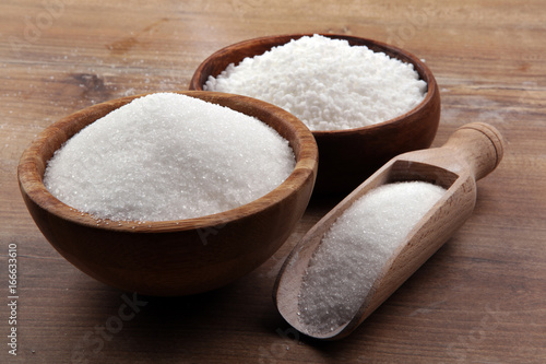 Quadro su tela Bowl and scoop with white sand and lump sugar on brown wooden background