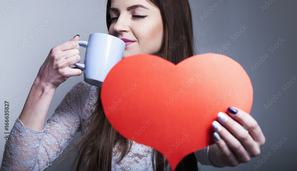 Beautiful young woman with cup of coffee shows that she loves this drink Beautiful young woman with cup of coffee shows that she loves this drink