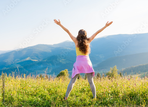 sporty young woman cheering open arms at mountain peak