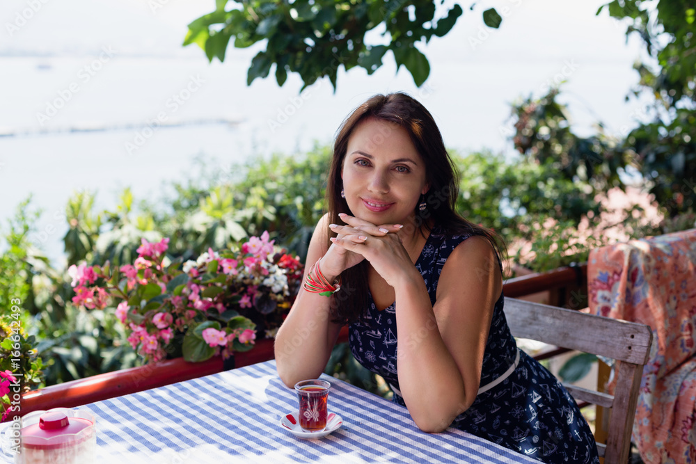 Fototapeta premium Young woman in cafe with glass of tea on the table