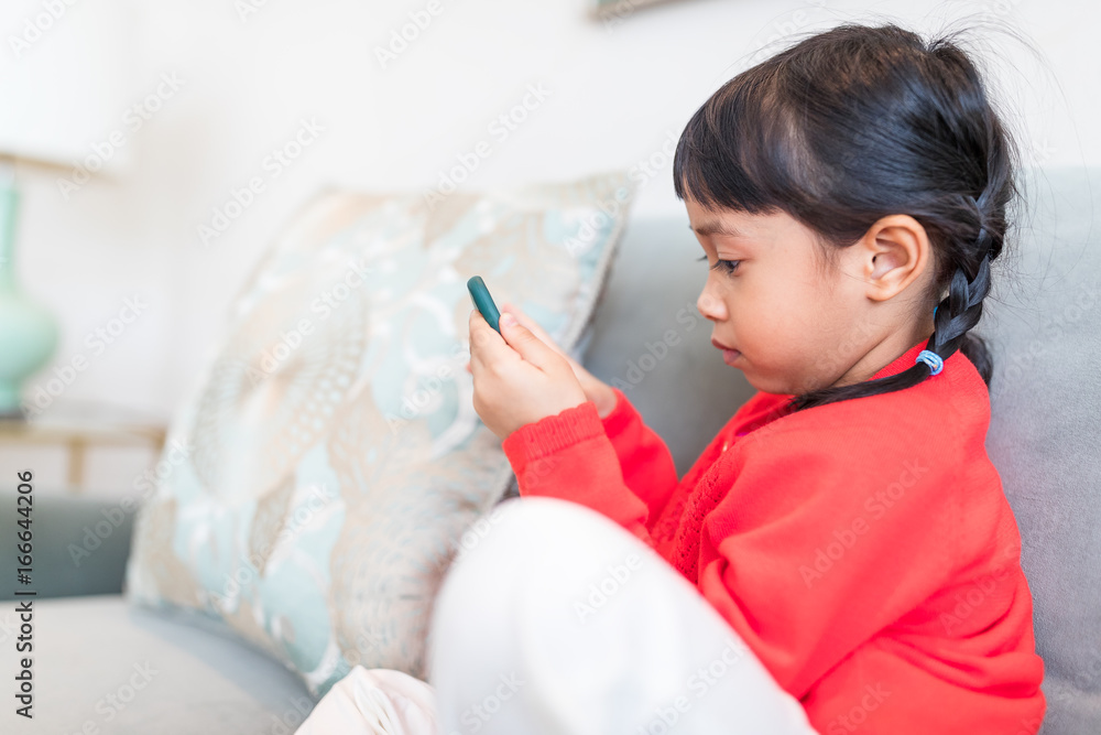 Asian girl looking at smart phone and sitting on sofa Asian girl looking at smart phone and sitting on sofa