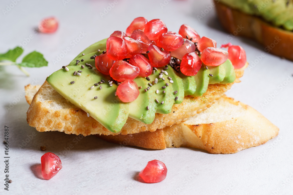 sliced avocado on toast bread with pomegranate seeds. sliced avocado on toast bread with pomegranate seeds.