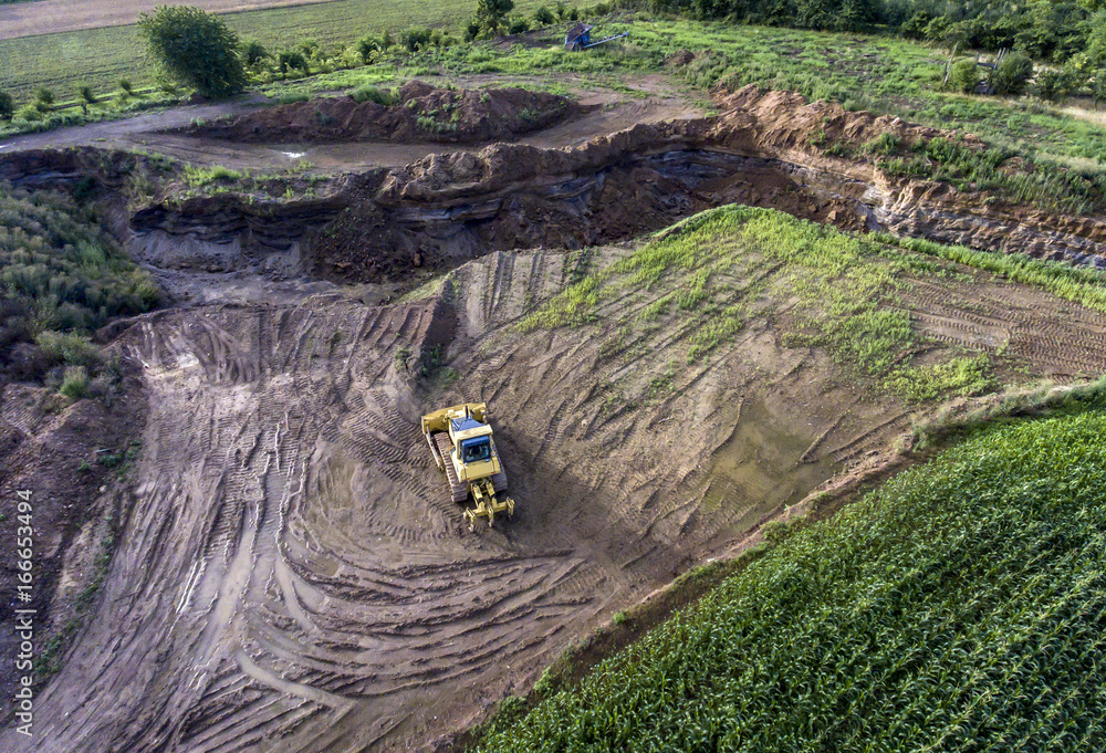 top view heavy machine excavator bagger working in mud on construction site with green landscape surrounding top view heavy machine excavator bagger working in mud on construction site with green landscape surrounding