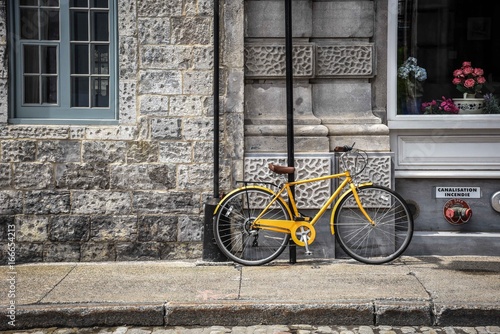 Yellow bike leaning against stone building in Montreal