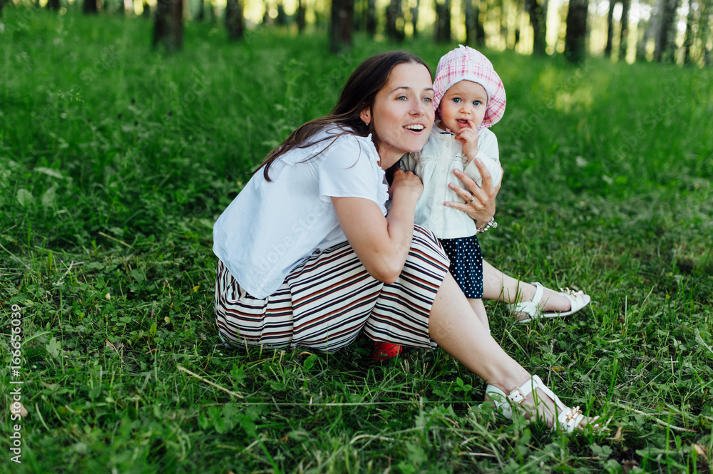 Fototapeta premium Funny mom with baby sitting on the grass