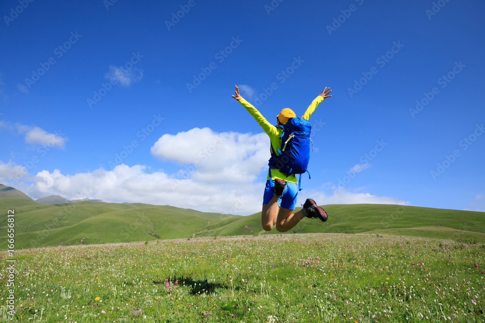 cheering young woman jumping in grassland mountain top cheering young woman jumping in grassland mountain top