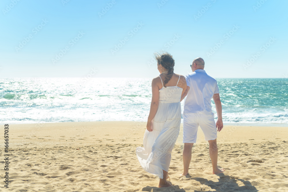Young romantic couple walking on the beach holding hands