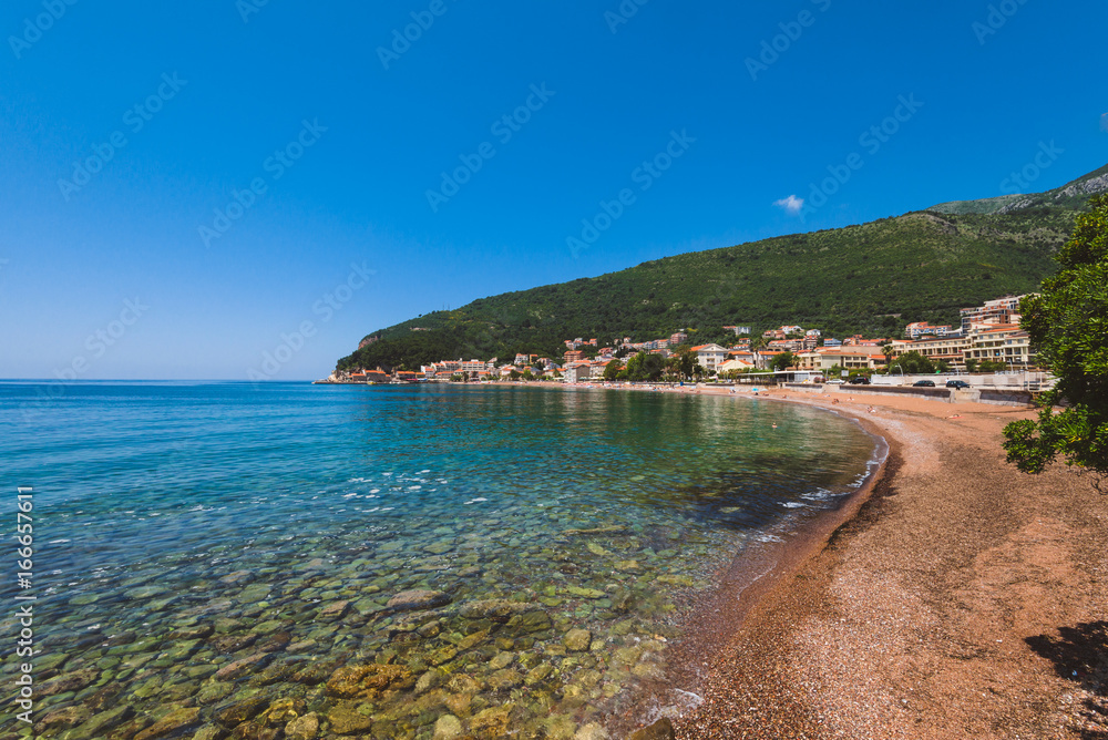Montenegro landscape with public beach in Petrovac village and sea view. Pebble beach on Montenegrin coast with clear water and by summer day.