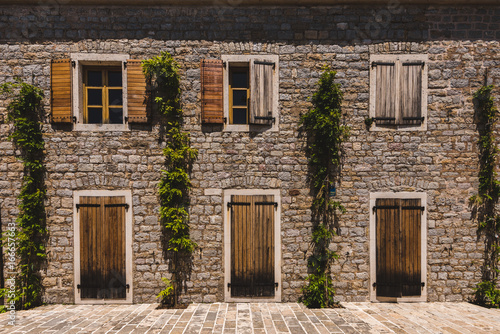 Traditional barrack building in Citadela complex in Budva, Montenegro. Ancient stone house with shattered windows and green ivy in Budva Old Town by sunny day.