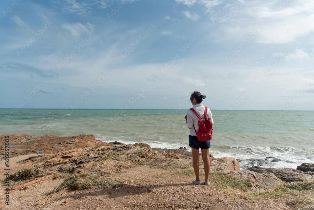 Happy young traveler with a backpack, enjoying the view of a tropical beach on a background the mountains. Young backpacker traveling along Asia, happy female walking discovering world