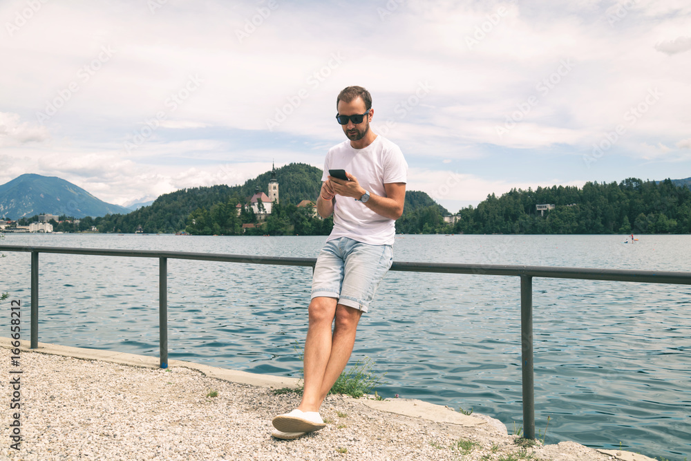 Modern guy using cellphone on the lake.