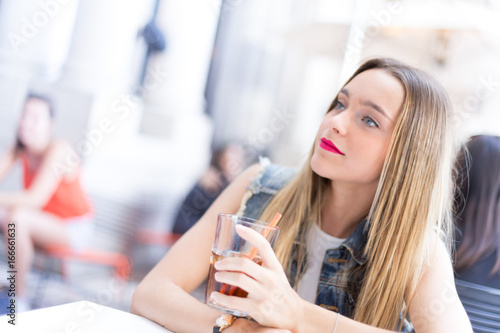 Happy young girl drinking a cocktail outdoor, during a sunny summer day