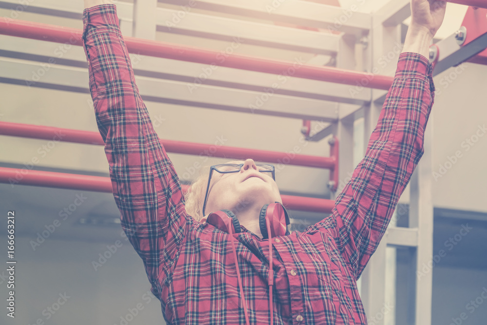 Φωτογραφία Man with glasses and a red shirt hanging on a bar in gym. Toned