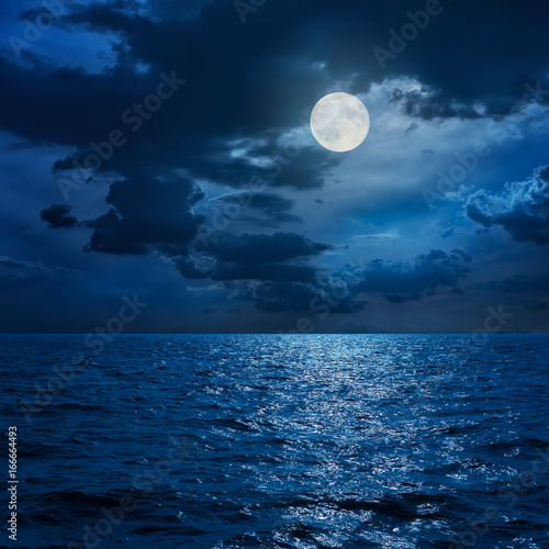 full moon in clouds over sea in night