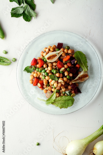 Fresh chickpea salad with mint and vegetables on white rustic background. Healthy lunch concept. Composition with copy space