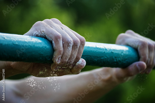 young man holding hands on the horizontal bar