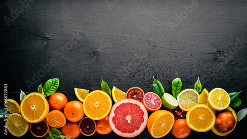 Fresh citrus fruits. Lemon orange, tangerine, lime. On a black background Wooden. Top view.