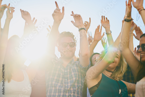 Group of people dancing at summer festival, hands raised