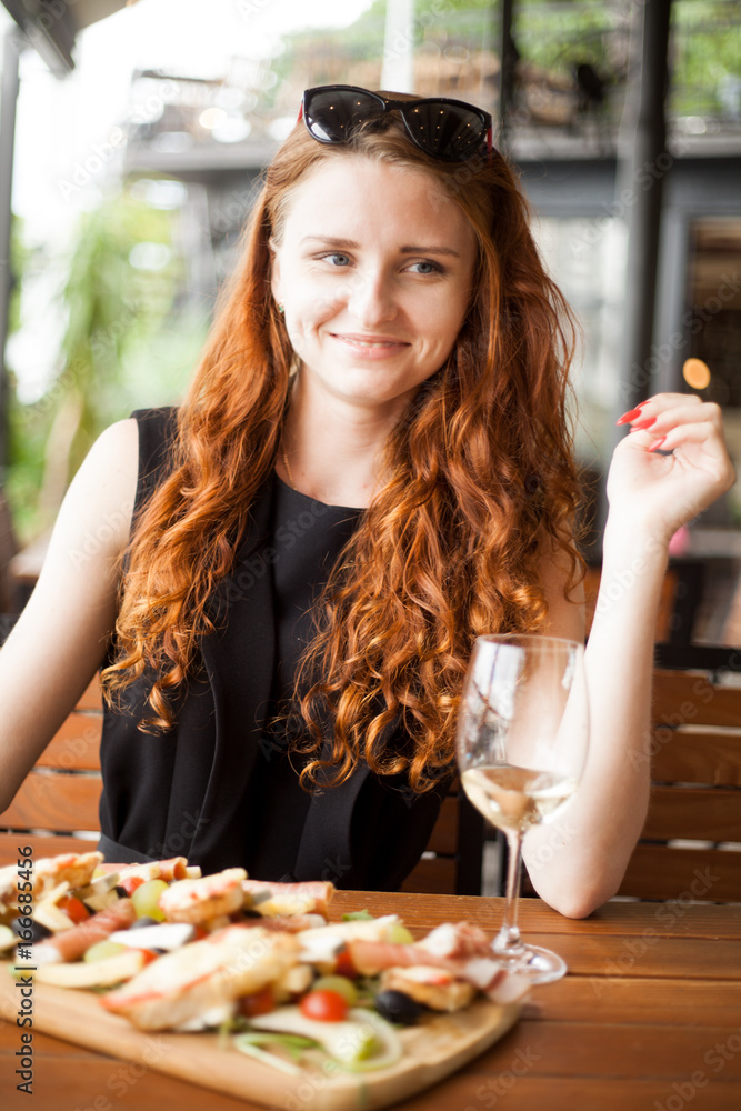Redhead woman eating and drinking wine in restaurant