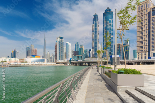 Fototapeta Dubai - The skyscrapers over and the promenade of new Canal and Burj Khalifa in the background