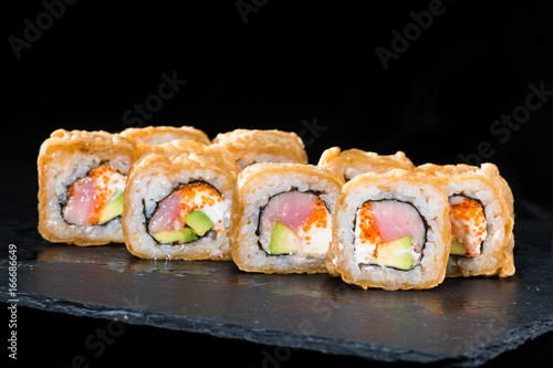 Traditional Japanese cuisine. Selective focus on sushi rolls with salmon, cream cheese, rice, cucumber, caviar and raw meat on dark background