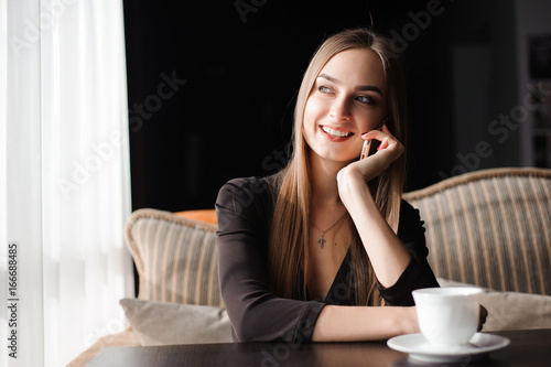attractive female with cute smile having talking conversation with mobile phone while rest in cafe