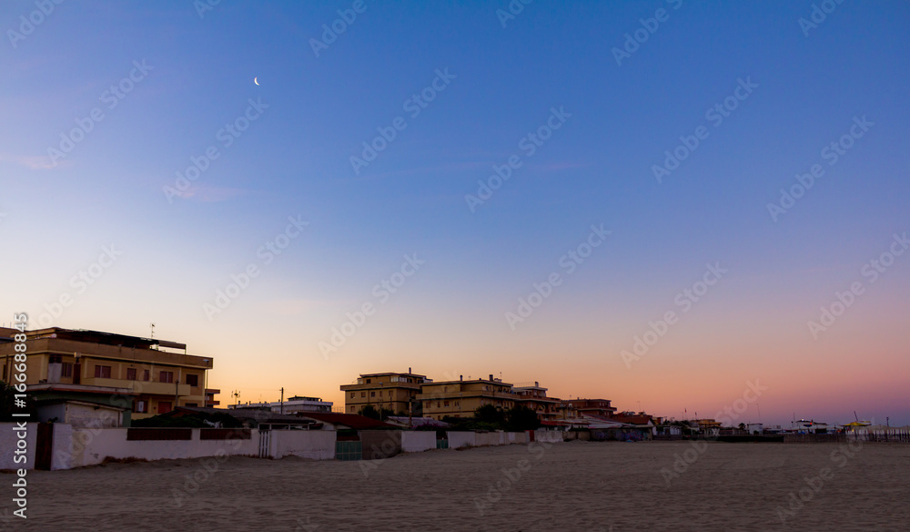 Sunrise colours and moon over beach