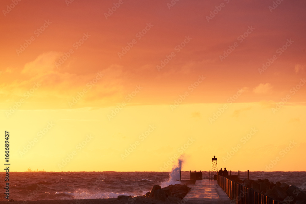 wave hits the pier at sunset in nr. Vorupoer at the North Sea Coast in Denmark