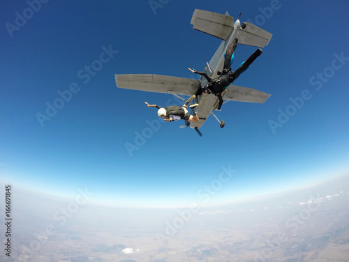 Two skydivers jump from an airplane