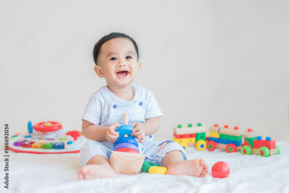 Adorable Asian baby boy 9 months sitting on bed and playing with color developmental toys at home.. Adorable Asian baby boy 9 months sitting on bed and playing with color developmental toys at home..