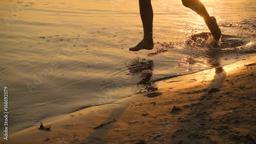 Silhouette of two kids running to beach at sunset