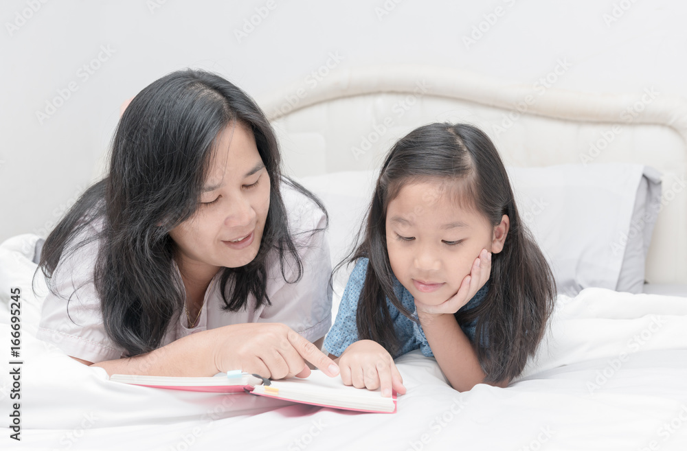 Mother and daughter reading book on bed Mother and daughter reading book on bed