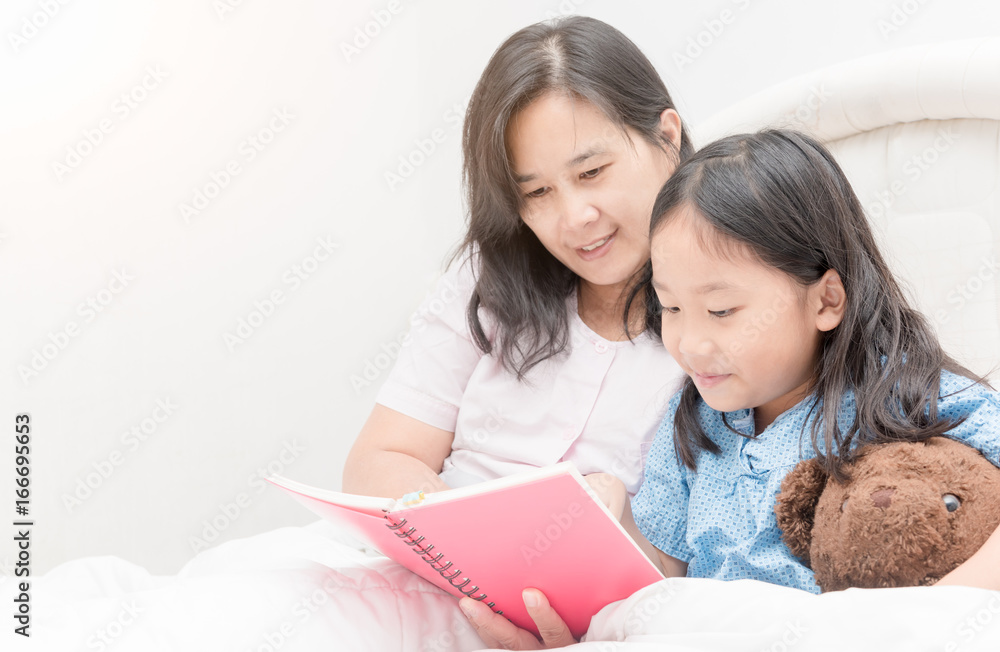 Mother and daughter reading book on bed, Mother and daughter reading book on bed,